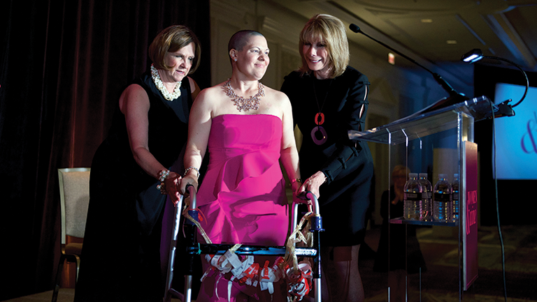 Event co-chairs Janet Davis (left) and Barbara McDuffie (right) help awardee Susan Miller to the podium.