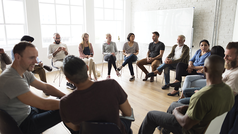 group of diverse people sitting in a circle of chairs