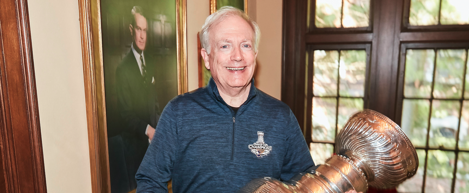 Tom Schlafly holding the Stanley Cup in front of a photo of his father, Daniel Schlafly Sr. (C’33)