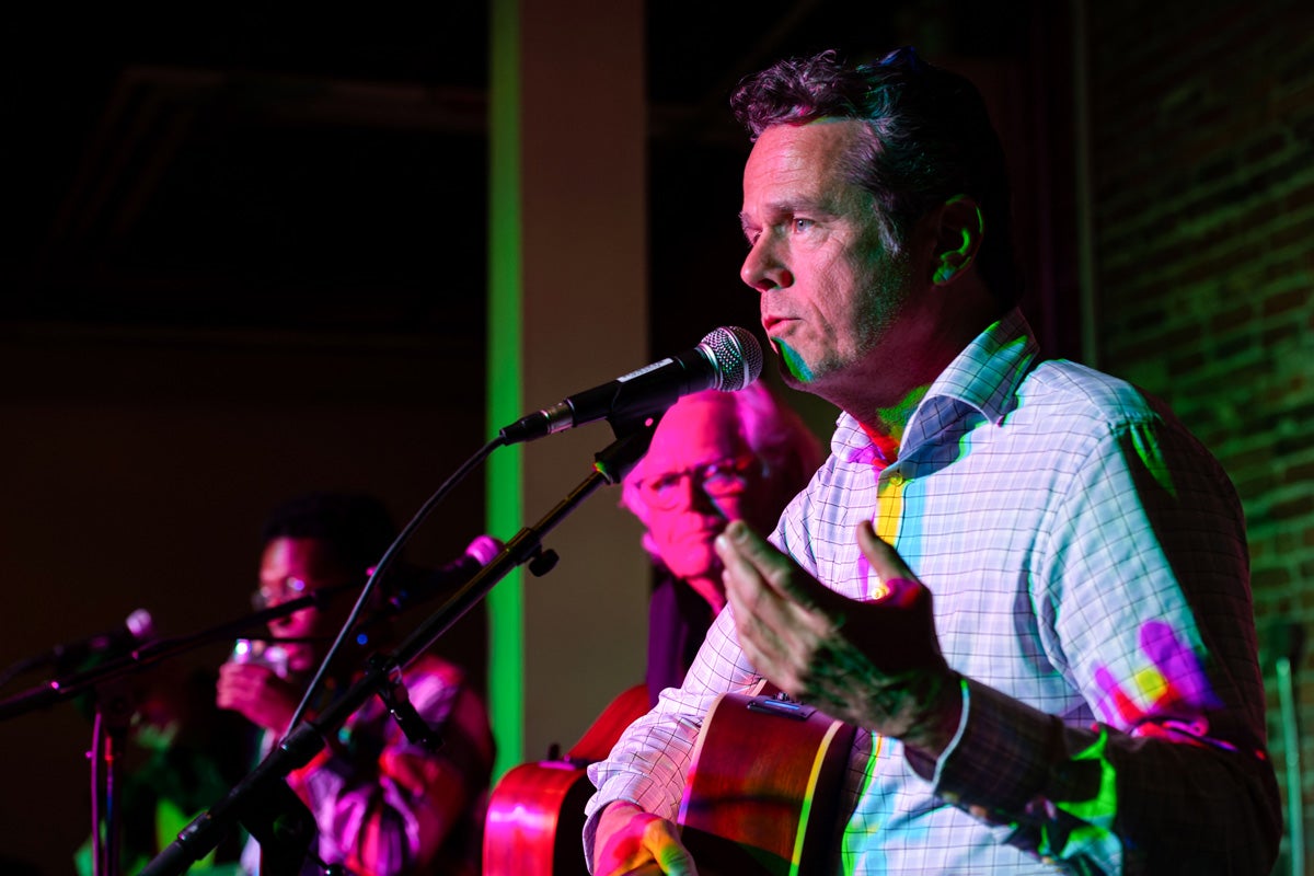 a man sings onstage while surrounded by colorful lights