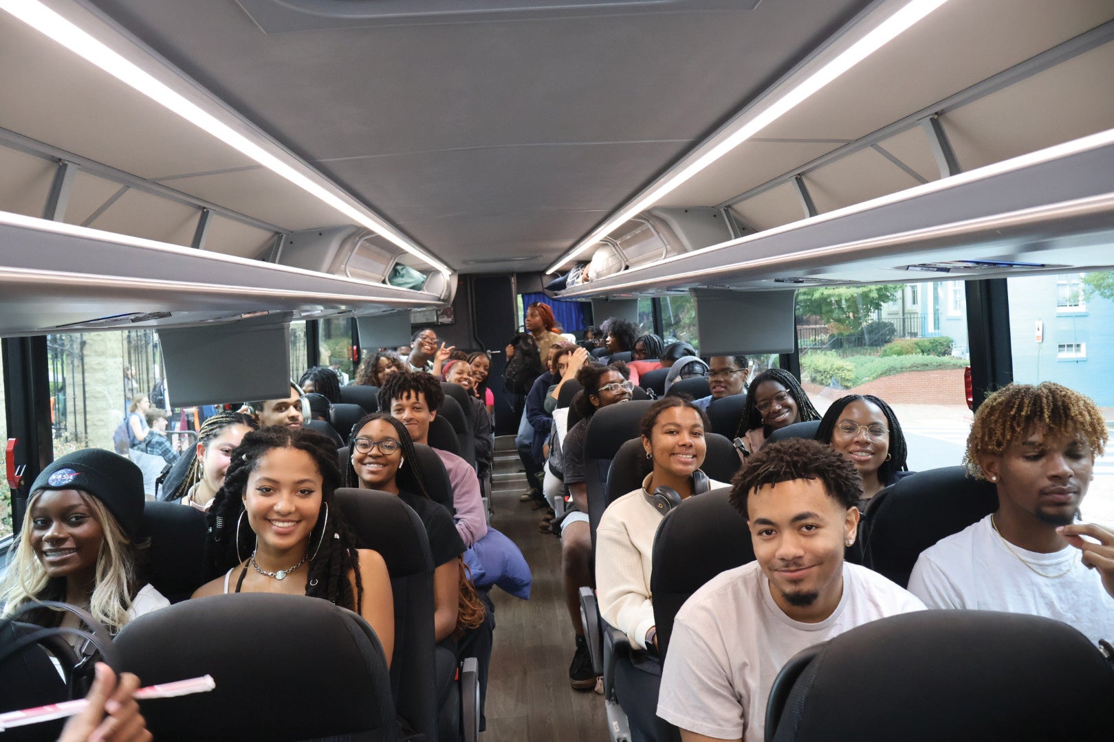rows of students smile while sitting inside a bus