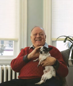 a man in a red sweater with a black and white small dog