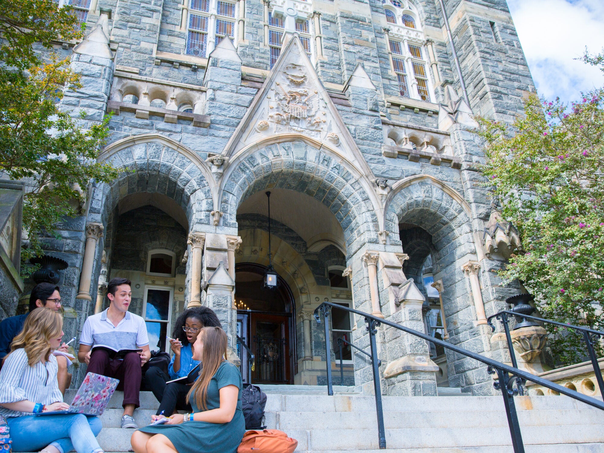 students chatting on the step of healy hall