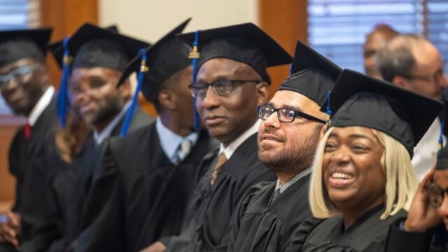people in graduation caps and gowns smile