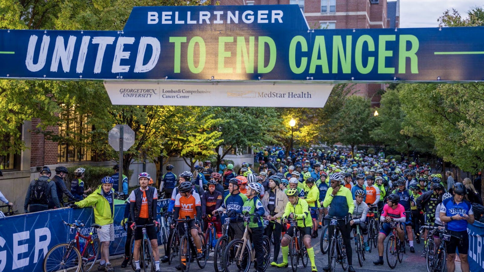 Many people stand with their bikes in front of the start line at a BellRinger event.