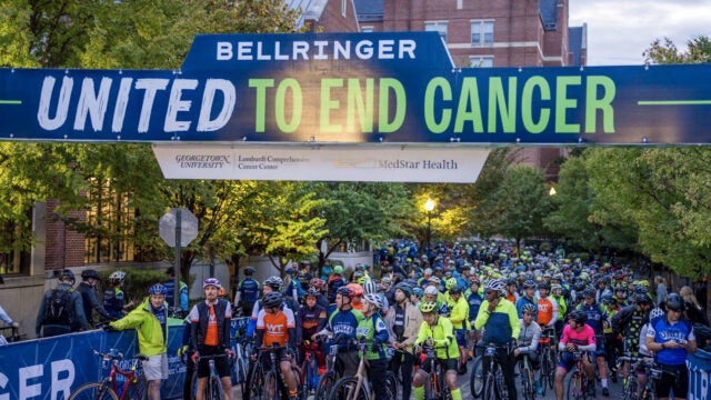 Many people stand with their bikes in front of the start line at a BellRinger event.