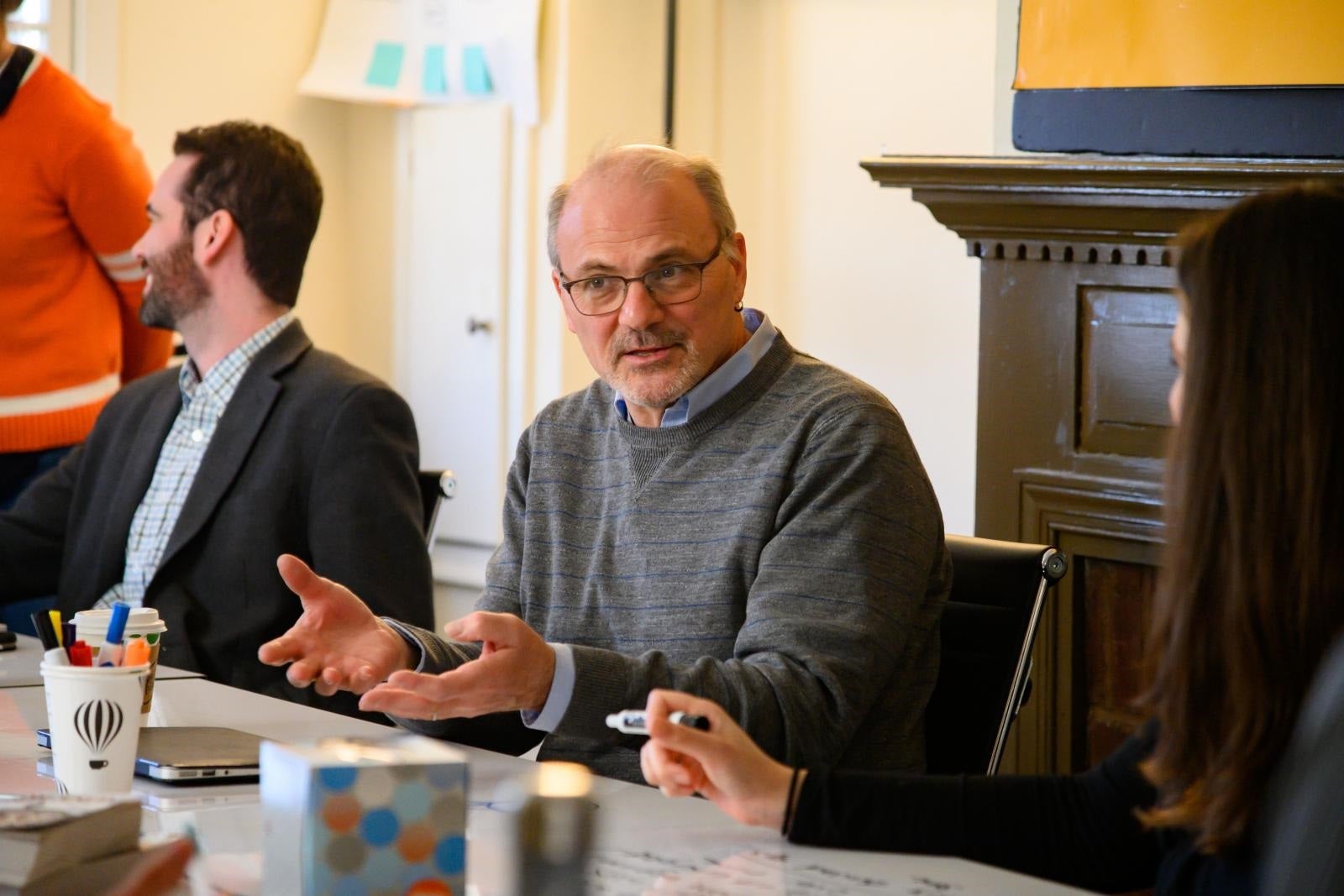 Randy Bass, seated at a table, leads a conversation at the Red House