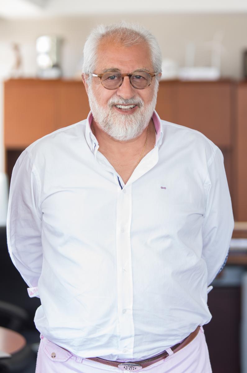 Rolando Gonzalez-Bunster smiling, wearing a white shirt and round brown glasses